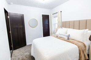 A bedroom with a bed, a round mirror, and two doors. - Stylish, comfort-first 2BR/1BA (Sioux Falls)