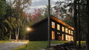 Una cabaña de troncos moderna con ventanas amplias, rodeada de un bosque.