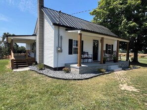 A single-story house with a porch, a chimney, and a small deck area.