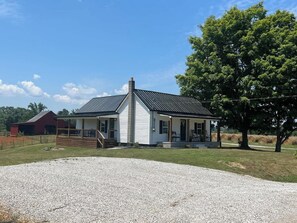 A single-story house with a front porch, a chimney, and a gravel driveway.