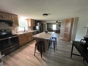 A kitchen with a central island, wooden cabinets, stainless steel appliances, and a hardwood floor.
