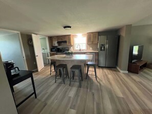 Una cocina moderna con una isla central, taburetes de bar y un refrigerador.