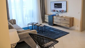 A modern living room with a sofa, a coffee table, a TV, and a small desk with a laptop. - Sunshine view 3 by Interhome (Reifnitz)