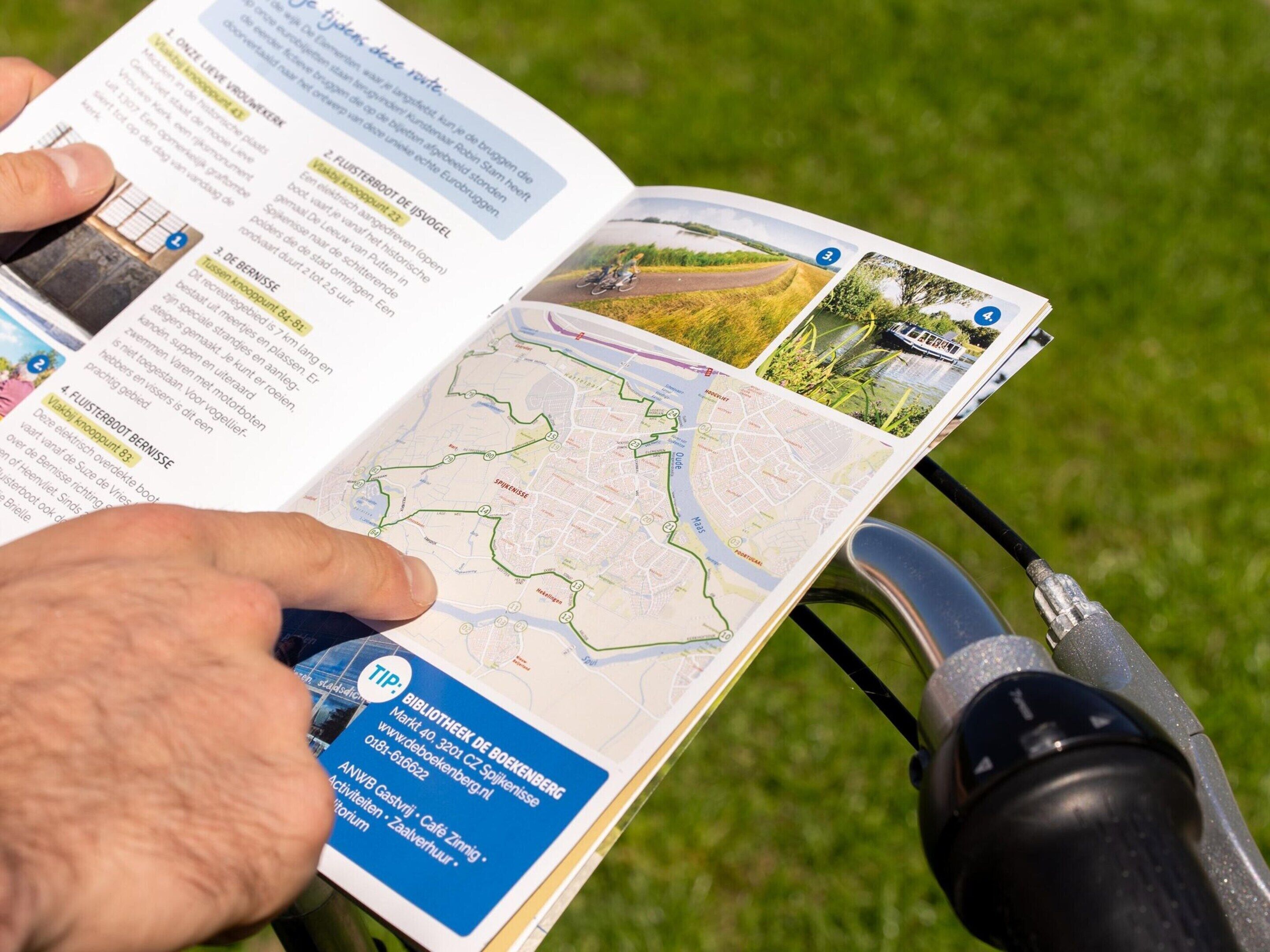 A person reading a map with a bicycle helmet attached to the handlebars.