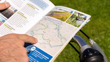A person reading a map with a bicycle helmet attached to the handlebars.