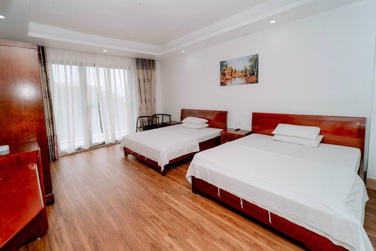 Ein Hotelzimmer mit zwei Einzelbetten, einem Holzschrank, einem Schreibtisch und einem Bild an der Wand.