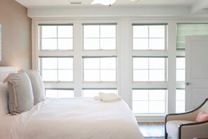 A bedroom with a large bed, multiple windows, and a door. - Sojourns Beach Views & Pool Family Home Sleeps 9 (Virginia Beach)
