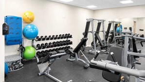 Et fitnesscenter med forskellig træningsudstyr, herunder håndvægte, træningsbolde og styrkemaskiner.