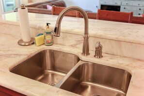 A kitchen with a double stainless steel sink, a marble countertop, and a faucet.