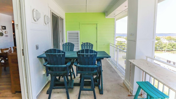 Een balkon met een groene deur, een tafel met stoelen en uitzicht op het landschap.