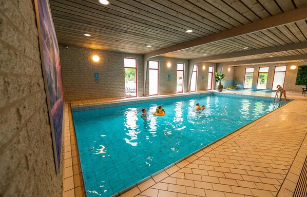 An indoor swimming pool with tiled walls, a wooden ceiling, and a brick floor. - Nice Chalet in a Holiday Park, Adjacent to the Hoge Veluwe National Park (Arnhem)