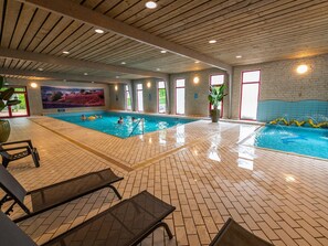 An indoor swimming pool with clear water, tiled floors, and a wooden ceiling. - Nice Chalet in a Holiday Park, Adjacent to the Hoge Veluwe National Park (Arnhem)