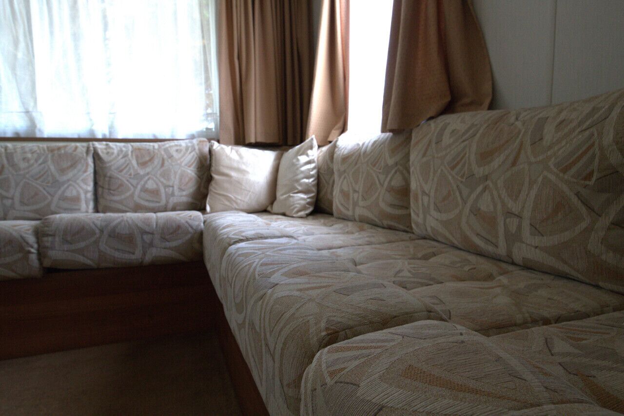 A sectional sofa with a geometric pattern, positioned near a window with curtains.