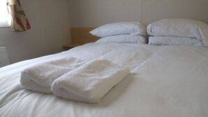 A neatly made bed with white linens and two folded towels on the bed. - WR2 Marlie Holiday Park (Kent)