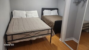 Un dormitorio con dos camas, un armario y una lámpara en el techo.