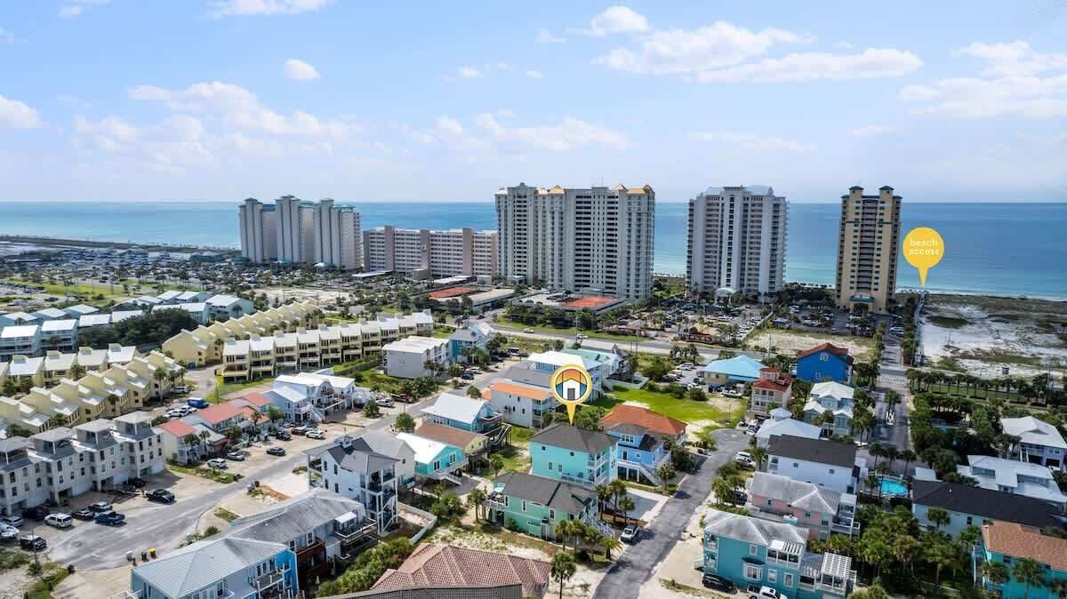An aerial view of a coastal residential area with multiple high-rise buildings, a beach, and a golf course.