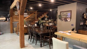 A dining area with a wooden table and chairs, a kitchen in the background, and a staircase leading upstairs. - Outdoor Oasis and Pickleball Paradise: Fishing, Paddle-boarding, Swimming (Augusta)