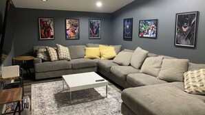 A living room with a grey sectional sofa, a white coffee table, and a patterned rug. - Outdoor Oasis and Pickleball Paradise: Fishing, Paddle-boarding, Swimming (Augusta)