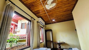 A hotel room with two beds, a ceiling fan, an air conditioning unit, a small table, and a window with curtains. - Silikhane Guest House (Luang Prabang)
