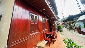 A wooden building with a balcony and a table with chairs outside. - Silikhane Guest House (Luang Prabang)