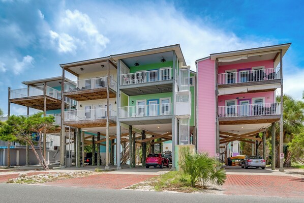 A multi-story building with balconies, a covered parking area, and a brick pathway. - Steps to Beach: Waterfront Cedar Key Home! (Cedar Key)