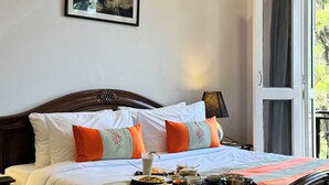 Ein ordentlich bezogenes Bett mit weißer und orangefarbener Bettdecke, ein Tablett mit Speisen und ein gerahmtes Bild an der Wand.