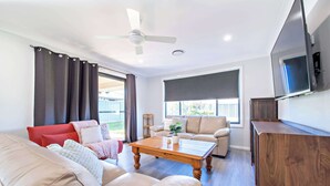 A modern living room with a sofa, a coffee table, and a TV. - Magnolia Entertainer. Firepit & Pets. Dubbo Family (Dubbo)