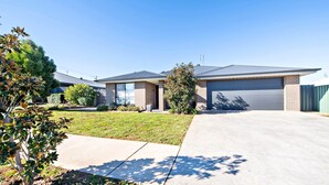 A residential house with a garage, a driveway, and a well-maintained lawn. - Magnolia Entertainer. Firepit & Pets. Dubbo Family (Dubbo)