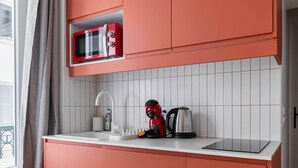 Una cucina compatta con forno a microonde, bollitore e lavandino.