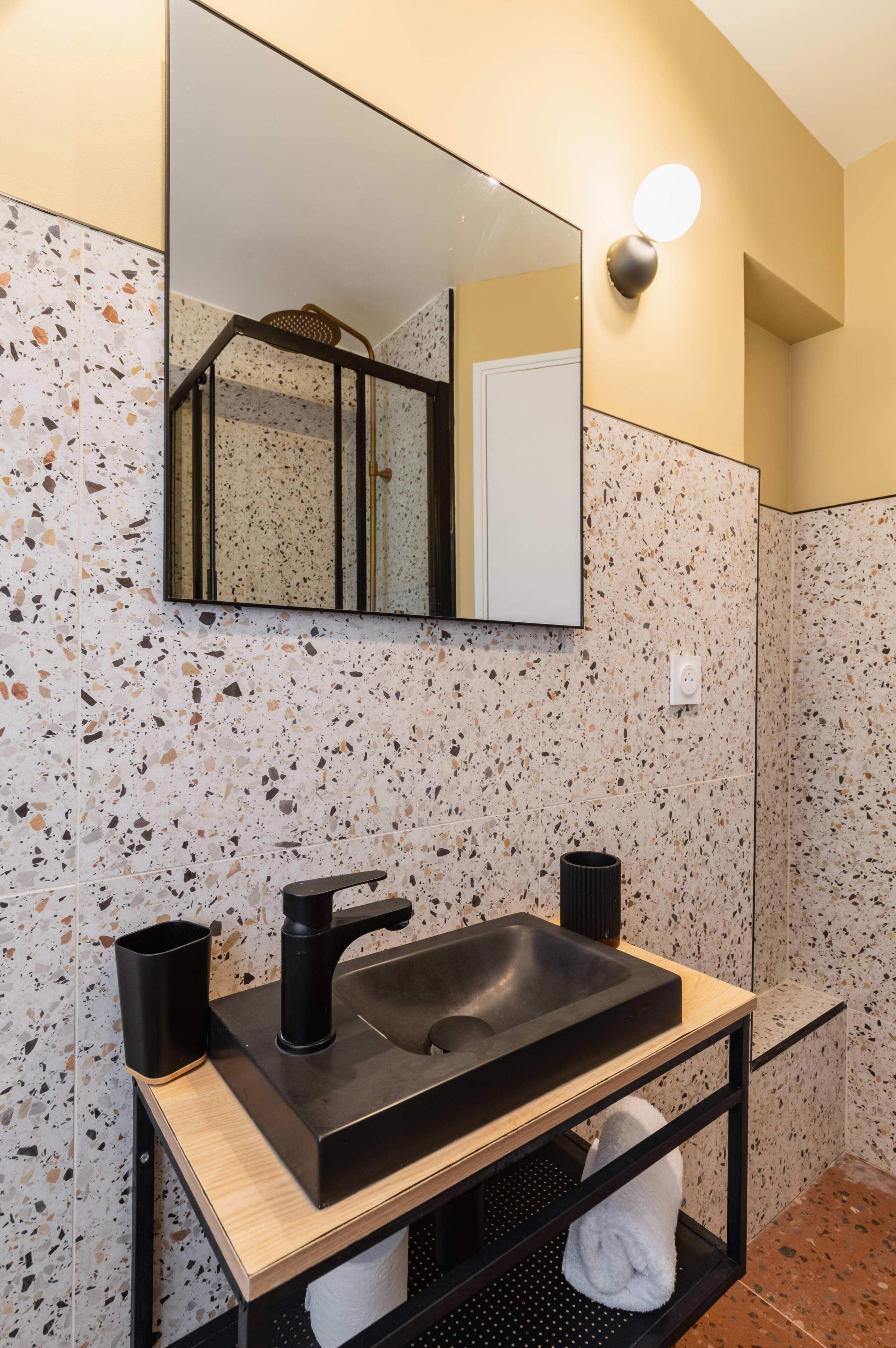 A bathroom with a black sink, a mirror, and a towel rack.
