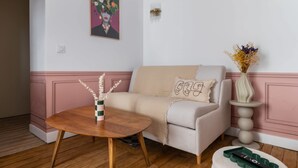 Un soggiorno con divano, tavolino, lampada a parete e un quadro.