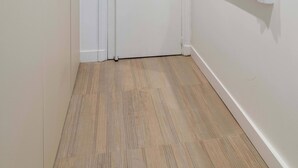Un corridoio con una porta bianca, una finestra con cornice bianca e un lampadario a soffitto.