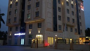 Un hotel de varios pisos con un diseño arquitectónico clásico, que presenta un cartel llamativo del hotel en el lado derecho.