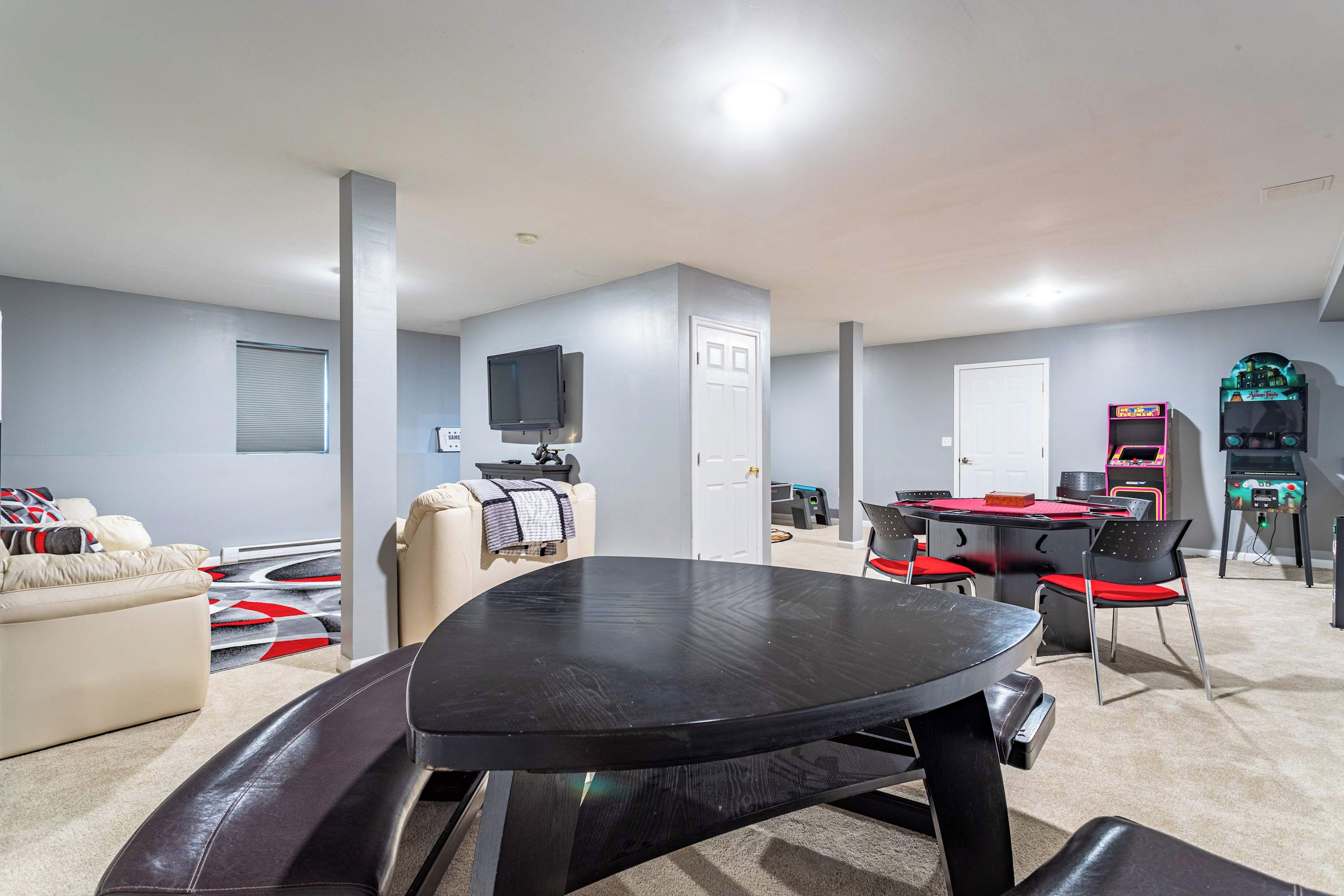 A living room with a black table, beige sofa, and a red and black carpet.