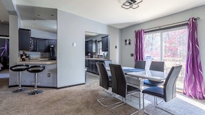 A modern kitchen with dark cabinets, a central island, and a dining area with a table and chairs.