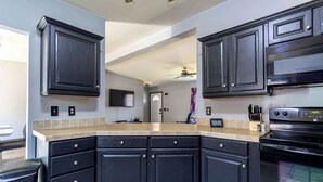 A modern kitchen with dark cabinetry, a built-in oven, and a beige countertop.