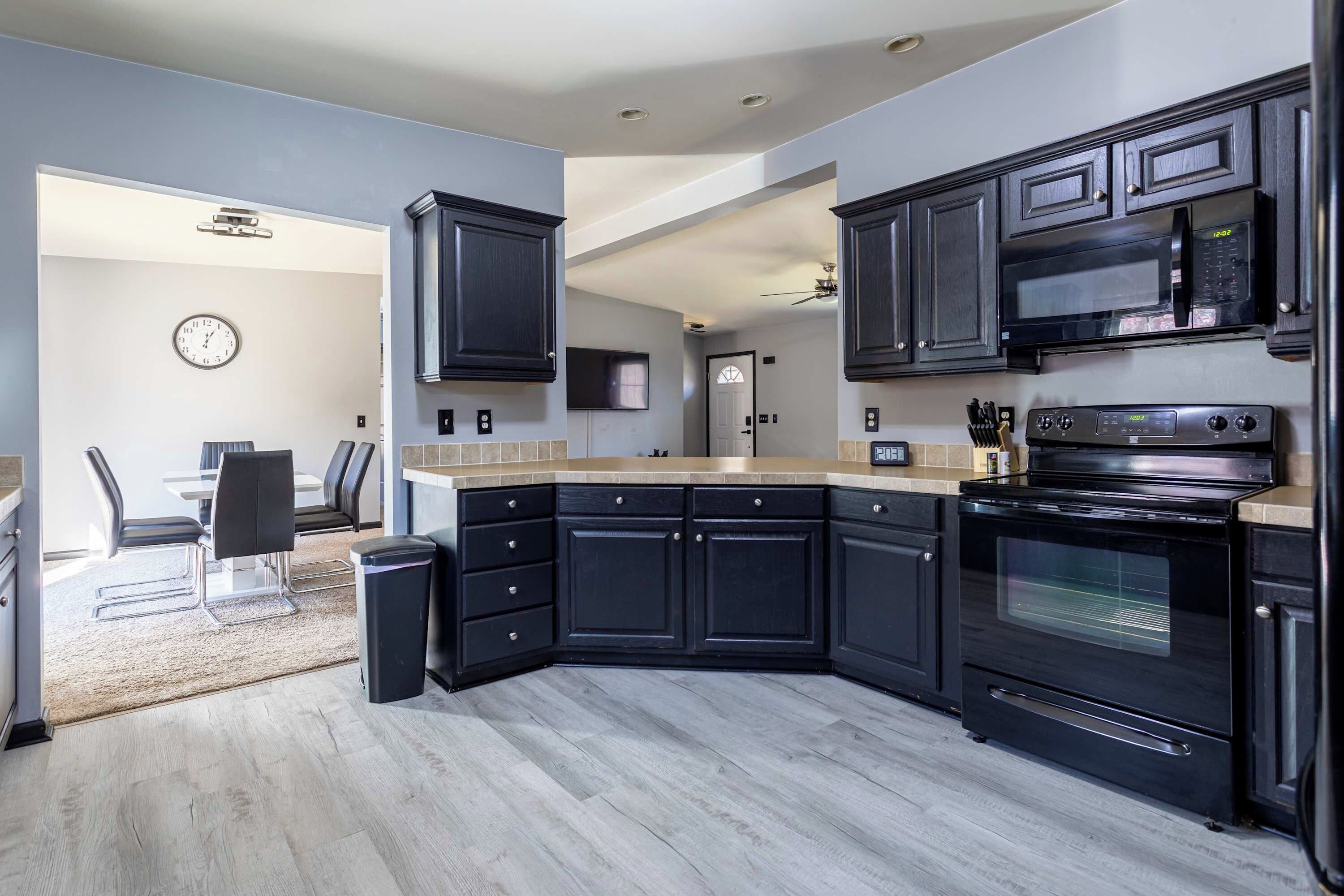 Una cucina moderna con mobili scuri, forno integrato e microonde.