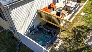 A hot tub on a deck with a wooden railing, surrounded by outdoor furniture.