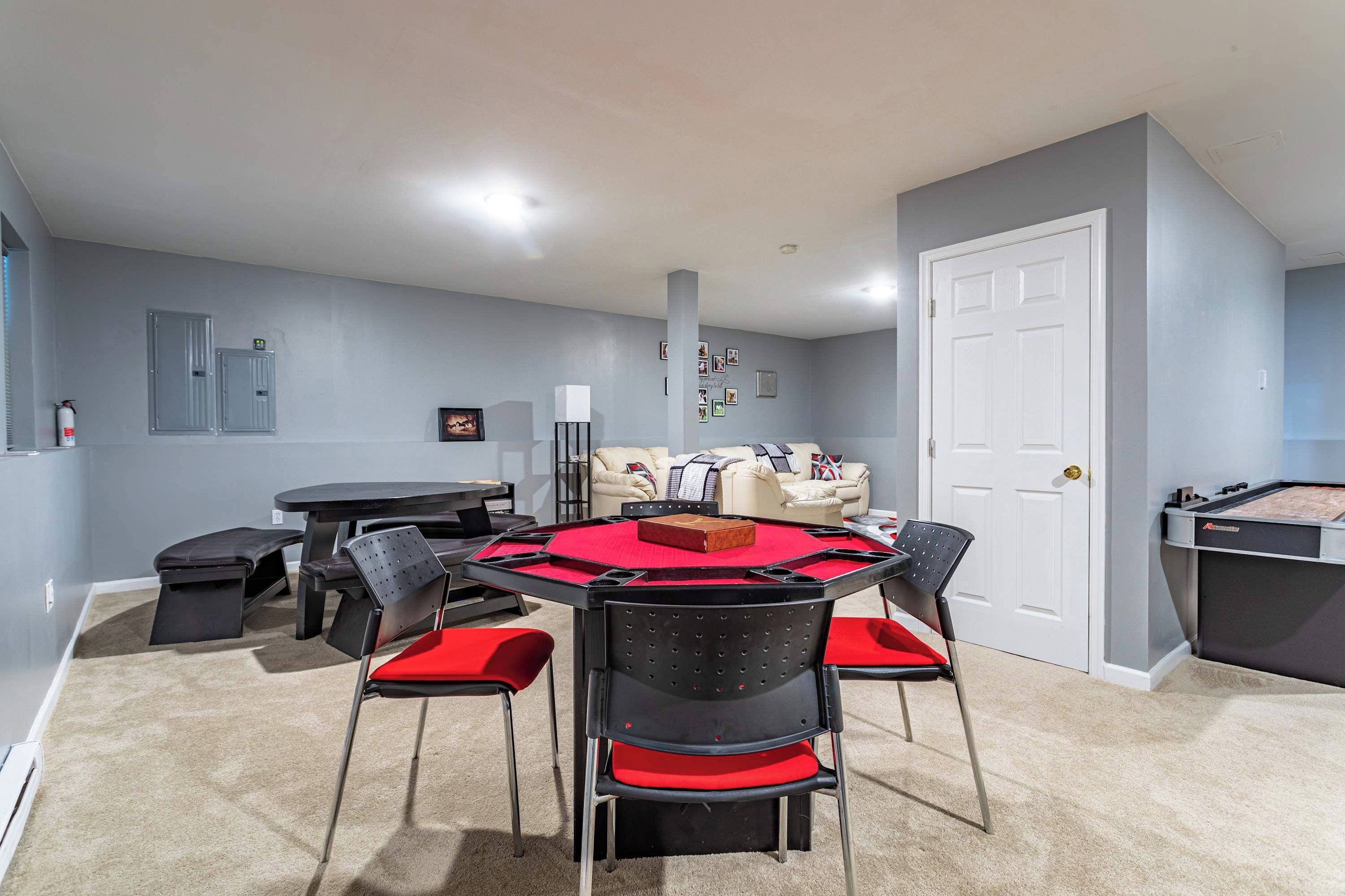 A room with a round table, four chairs, a sofa, a door, and a pool table.