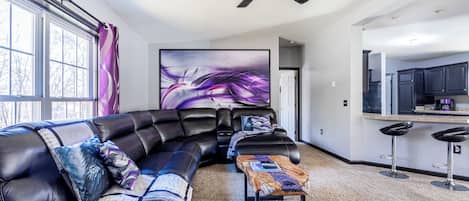 A modern living room with a sectional sofa, a coffee table, and a large abstract painting.