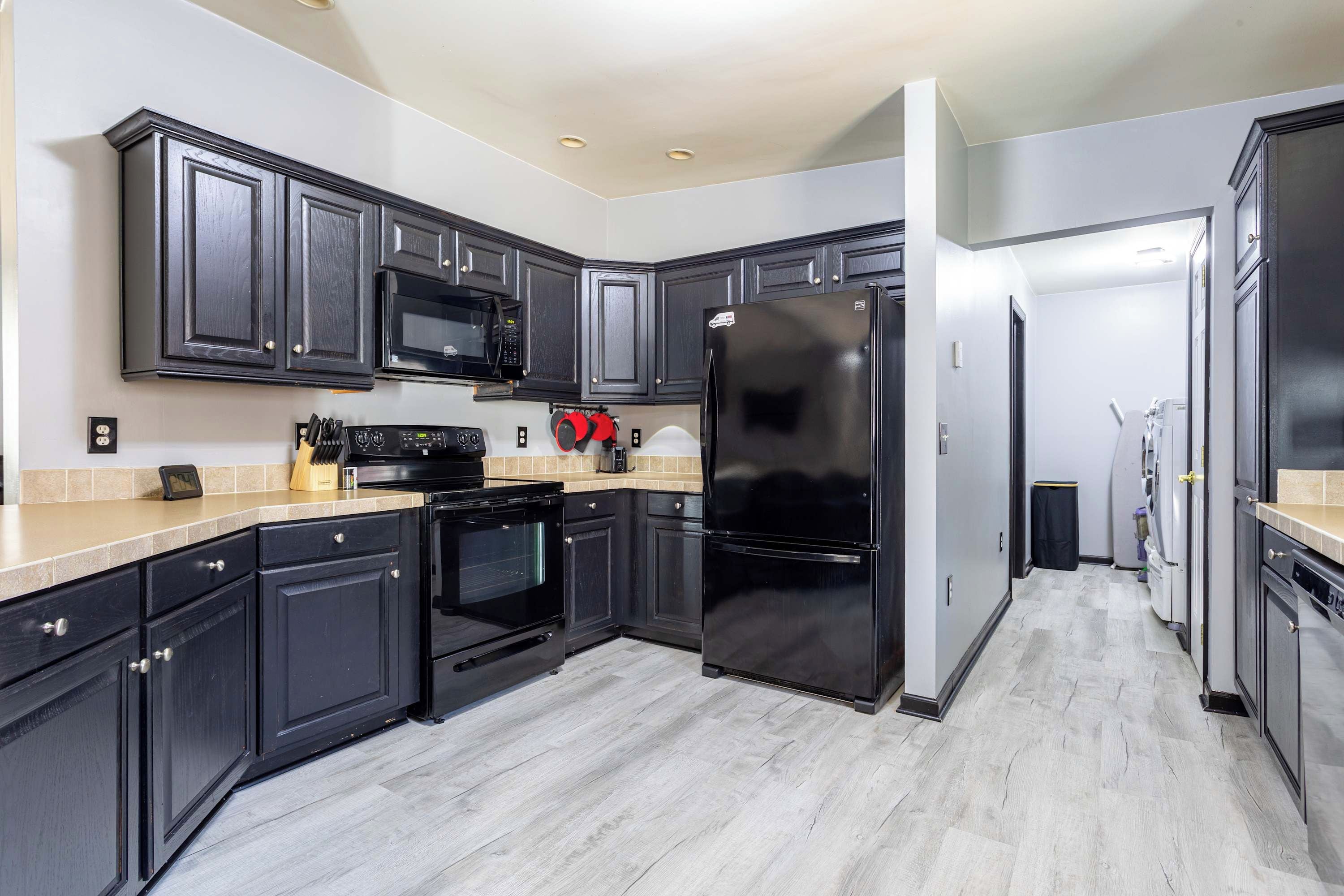 A modern kitchen with dark cabinetry, a black refrigerator, a microwave, and an oven.