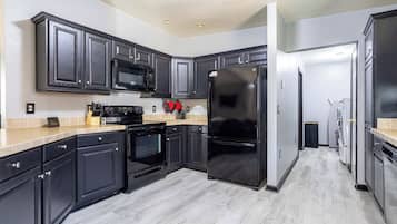 A modern kitchen with dark cabinetry, a black refrigerator, a microwave, and an oven.