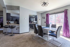 A modern kitchen with dark cabinets, a central island, and a dining area with a table and chairs.