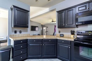 A modern kitchen with dark cabinetry, a built-in oven, and a beige countertop.