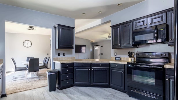 A modern kitchen with dark cabinetry, a built-in oven, and a microwave.