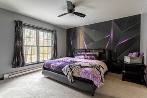 Un dormitorio con una cama, ventilador de techo, ventana y pared con diseños geométricos.