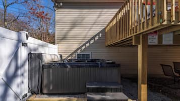 A hot tub area with a wooden deck, a covered seating area, and a sign indicating responsibility for accidents or injuries.