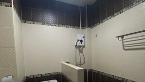 A bathroom with a toilet, a shower, and a towel rack. - Happyroom Airport Chiangrai (Chiang Rai)