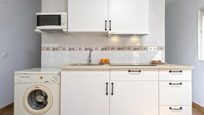 A compact kitchen with a washing machine, a microwave, and a sink.