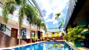 A swimming pool with a clear blue water surface, surrounded by palm trees and a building with a white facade and balconies. - Cityhotel Siem Reap (Siem Reap)